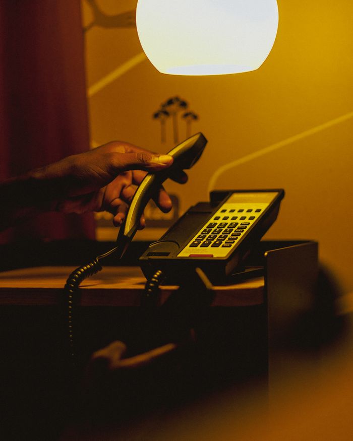 Contact A hand picks up a telephone handset in a warmly lit room, creating a moody ambiance.